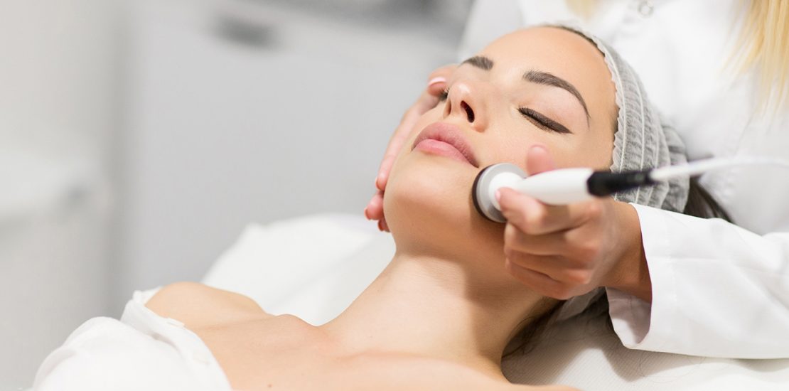 Beautiful young woman getting rejuvenating and tightening skin treatment at professional cosmetic salon.